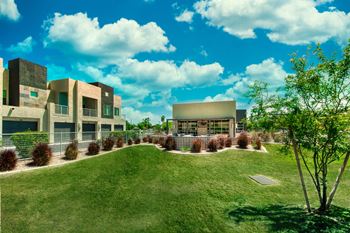 A modern building complex with a green lawn in front.