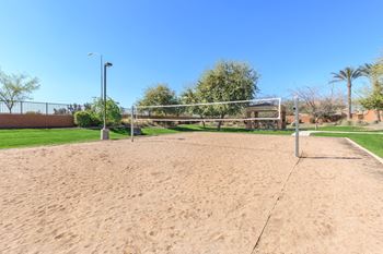 A sandy volleyball court with a net and a pole.