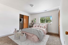 Post Falls townhouse for rent - a bedroom with white walls and a pink bed with a black and white striped comforter