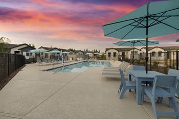 A poolside area with a table and chairs and a pool in the background.