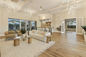 A spacious living room with a white sofa, a glass coffee table, and a rug.