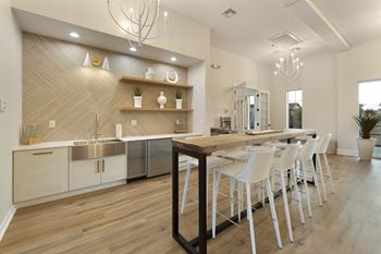 A modern kitchen with a wooden island and white chairs.