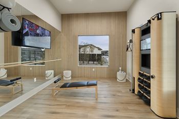 A room with a tv on the wall and a row of chairs.
