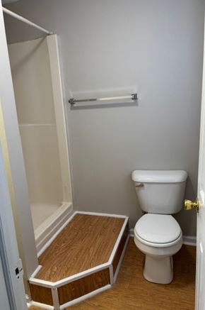 Newport News apartment for rent - A white toilet in a small bathroom with a wooden floor and a white door.