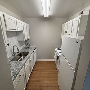 Newport News apartment for rent - a kitchen with white cabinets and a sink and a refrigerator