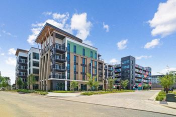 A modern multi-story residential building with balconies and a variety of windows.