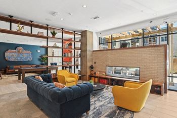 A living room with a blue couch and yellow chairs and a fireplace