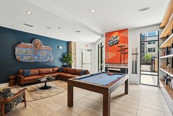 A pool table is in the middle of a room with a couch and a chair.