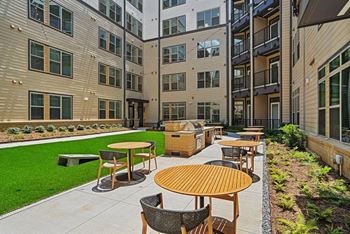 An outdoor patio with tables and chairs in front of an apartment building