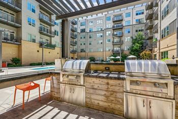 An outdoor kitchen with a grill and a pool in an apartment building