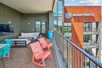 A balcony with a couch and chairs and a television