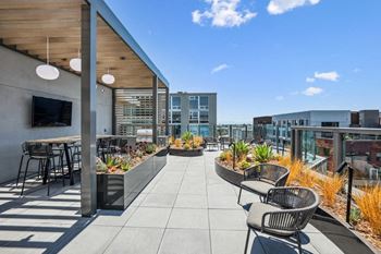 The settlement rooftop patio with tables and chairs and a tv