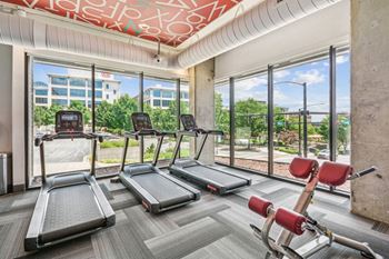 A gym with cardio machines and a view of the city