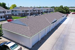 Kearney apartment for rent - A long white building with a grey roof is surrounded by cars and other buildings.