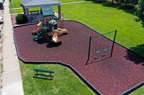 Kearney apartment for rent - A playground with a red rubber surface and a green slide.
