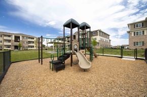 Evans apartment for rent - A playground with a slide, swings, and a seesaw in the foreground with apartment buildings in the background.