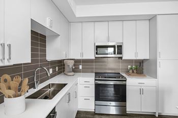Varietal design package: featuring grey elm upper and lower cabinets, white subway tile backsplash and snow-white polished quartz countertops.
