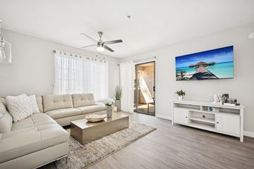 Tempe apartment for rent - A living room with a white sofa, a coffee table, and a painting of a beach scene on the wall.