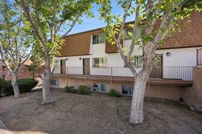 Reno apartment for rent - A tree stands in front of a building with a balcony.