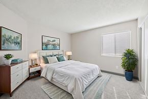 Henderson apartment for rent - A bedroom with a large bed, a dresser, and a potted plant.