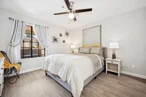 Tempe apartment for rent - A bedroom with a bed, a chair, a ceiling fan, and a painting on the wall.