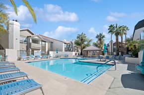 Las Vegas apartment for rent - A swimming pool surrounded by sun loungers and palm trees.