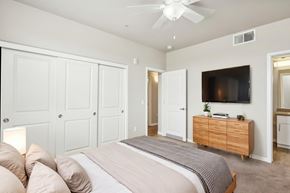 Sacramento apartment for rent - A bedroom with a large bed, a ceiling fan, and a TV mounted on the wall.