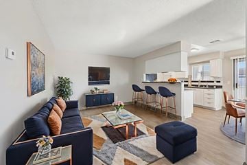 Henderson apartment for rent - A living room with a dark blue couch and a coffee table with a vase of flowers on it.