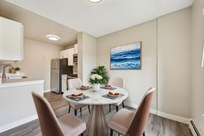 Denver apartment for rent - A dining room with a table set for two and a painting of the ocean on the wall.