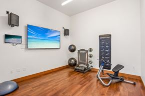 Lynnwood apartment for rent - A home gym with a TV, weights, and exercise equipment.