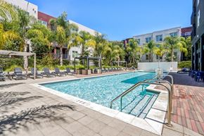 San Jose apartment for rent - a swimming pool with chairs and a building in the background