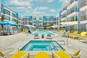 Phoenix apartment for rent - A large pool surrounded by yellow chairs and umbrellas.