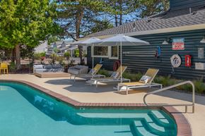 Kent apartment for rent - A pool with a sun lounger and umbrella next to a building.