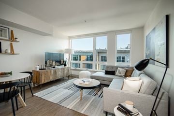 Seattle apartment for rent - a living room with a large window and a couch and a table