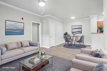 Tracy apartment for rent - A living room with a grey couch, a glass coffee table, and a painting of a beach scene on the wall.