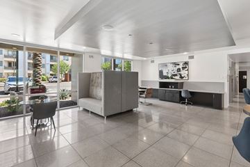 Phoenix apartment for rent - A spacious living room with a grey sofa and a large window overlooking a parking lot.