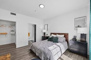 Aurora apartment for rent - A bedroom with a bed, nightstand, and a mirror on the wall.