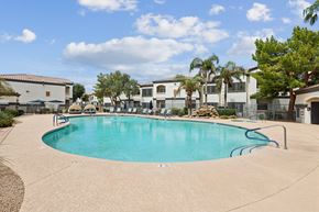 Chandler apartment for rent - A swimming pool surrounded by palm trees and buildings.