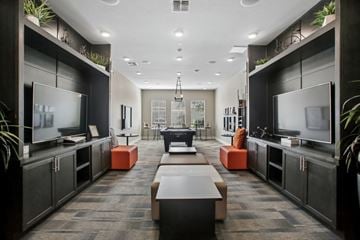 Sacramento apartment for rent - A modern living room with a long table and two TVs.