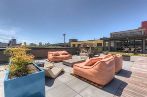 Seattle apartment for rent - A rooftop patio with orange chairs and a blue planter box.