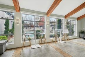 Hillsboro townhouse for rent - A room with a table and chairs in front of a window with a view of a pool and trees.