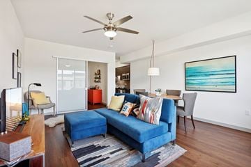 Hillsboro apartment for rent - A living room with a blue couch and a ceiling fan.