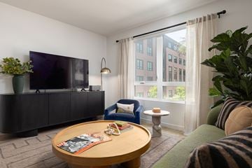 Santa Clara apartment for rent - A living room with a flat screen TV on a cabinet and a sofa with a striped blanket on it.