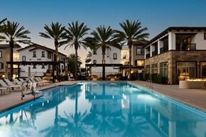 Vista apartment for rent - A swimming pool surrounded by palm trees and lounge chairs in front of a building.