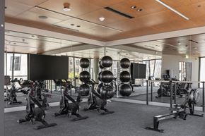 Oakland apartment for rent - a gym with exercise bikes and weights on a mirrored wall