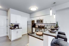 Bothell apartment for rent - A kitchen with white cabinets and a black bench.