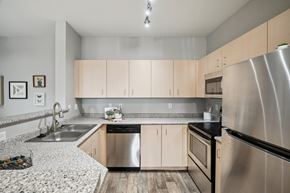 Hillsboro townhouse for rent - A modern kitchen with a stainless steel refrigerator and wooden cabinets.