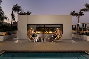 Huntington Beach apartment for rent - Two people sitting by a pool in front of a modern house.