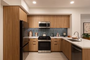 Huntington Beach apartment for rent - A modern kitchen with wooden cabinets and a black stove top oven.