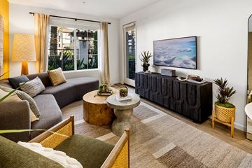 Vista apartment for rent - A living room with a grey couch, a wooden table, and a painting on the wall.
